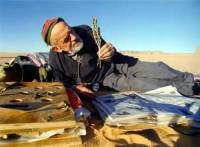 La photo originelle de Théodore Monod tenant une plante au milieu du désert.